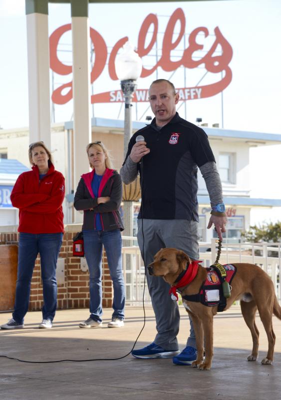 Veteran Jason Harrar stands with Loftus, his service dog named after a fallen soldier. Gold Star mother Karen Vaughn, left, and Heather Lloyd from Tails of Valor listen as Harrar tells his story.